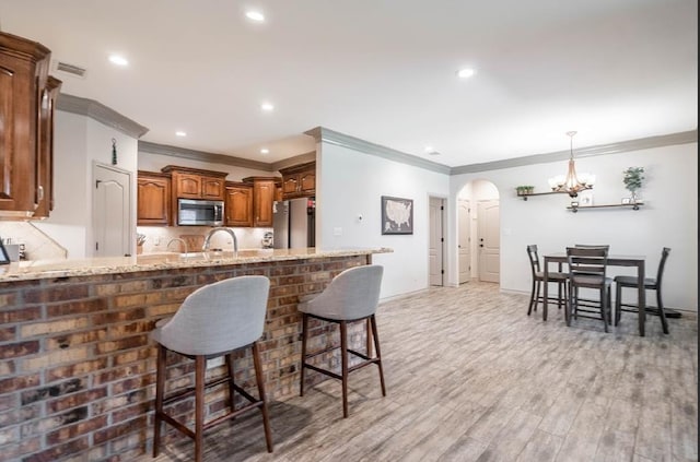 4402 Guadalupe, Midland, TX 79707 - kitchen with appliances with stainless steel finishes, crown molding, a peninsula, arched walkways, and a chandelier