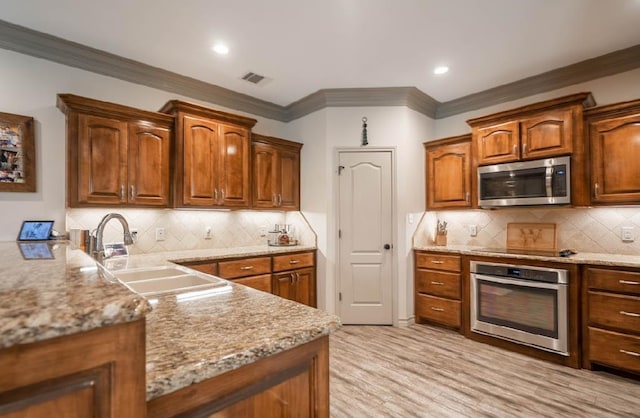 4402 Guadalupe, Midland, TX 79707 - kitchen featuring appliances with stainless steel finishes, ornamental molding, decorative backsplash, brown cabinetry, and light stone countertops
