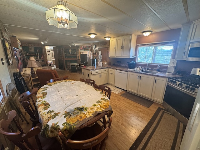 303 Squaw Valley Trl, Fort Davis, TX 79734 - kitchen with appliances with stainless steel finishes, a peninsula, light wood-style flooring, a chandelier, and white cabinets