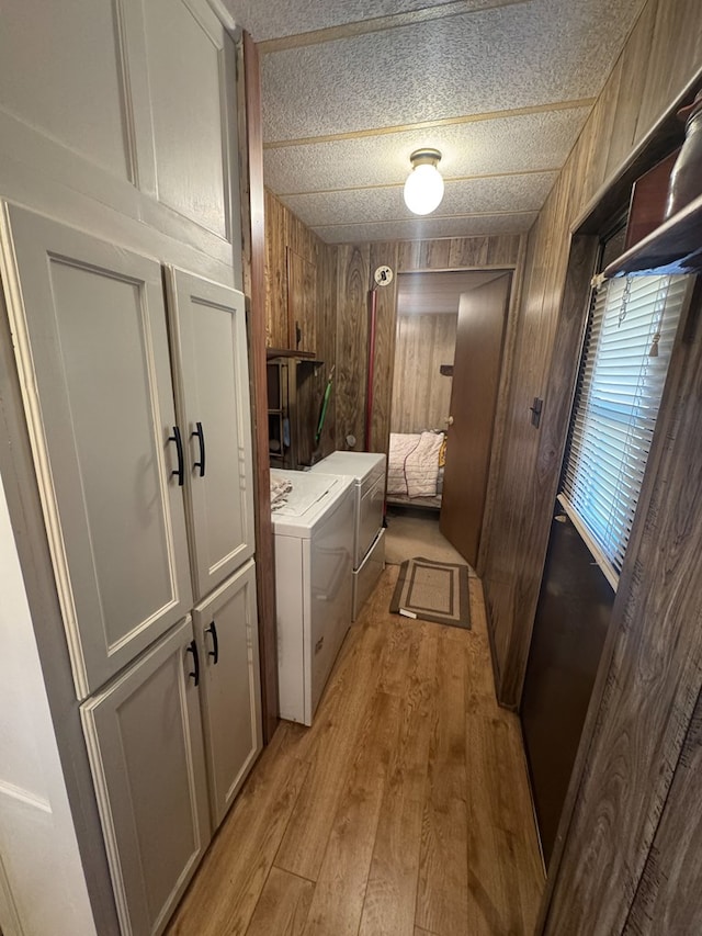 303 Squaw Valley Trl, Fort Davis, TX 79734 - laundry area with light wood-style floors, washer and dryer, cabinet space, and wood walls