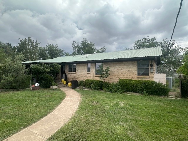 407 N Phelps St, Alpine, TX 79830 - rear view of house featuring a lawn, stone siding, and metal roof