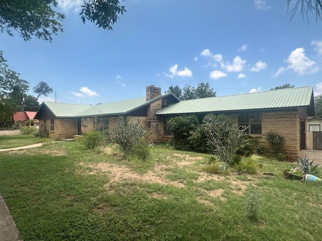 407 N Phelps St, Alpine, TX 79830 - view of side of property featuring a chimney, metal roof, and a yard