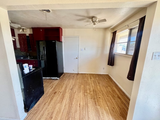3501 Merrill Ave, Odessa, TX 79764 - kitchen with black fridge with ice dispenser, a ceiling fan, light wood-style flooring, and stove