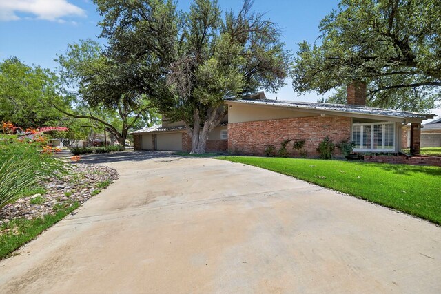2720 Fair Oaks Cir, Odessa, TX 79762 - view of front facade featuring brick siding, concrete driveway, a front lawn, a chimney, and a garage
