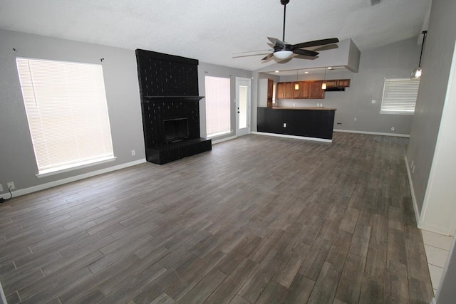 1721 E 56th St, Odessa, TX 79762 - unfurnished living room featuring ceiling fan, dark wood-type flooring, baseboards, and lofted ceiling