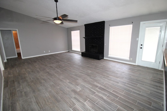 1721 E 56th St, Odessa, TX 79762 - unfurnished living room featuring a ceiling fan, dark wood-type flooring, baseboards, a fireplace, and vaulted ceiling