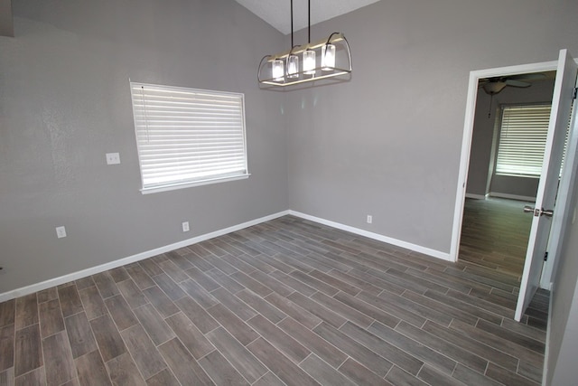 1721 E 56th St, Odessa, TX 79762 - empty room featuring baseboards, healthy amount of natural light, lofted ceiling, dark wood-style flooring, and a chandelier