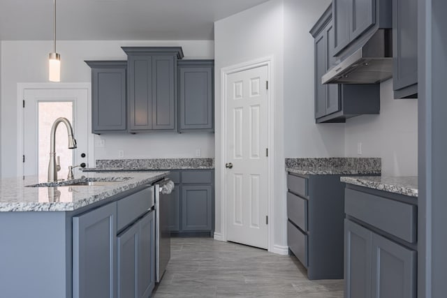 309 S Hancock Ave, Odessa, TX 79761 - kitchen featuring under cabinet range hood, light stone countertops, decorative light fixtures, and a kitchen island with sink