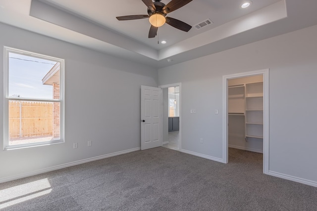 309 S Hancock Ave, Odessa, TX 79761 - unfurnished bedroom with a tray ceiling, multiple windows, carpet floors, a spacious closet, and recessed lighting