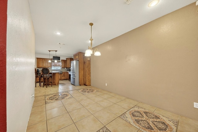 1321 Lindberg St, Odessa, TX 79763 - kitchen featuring freestanding refrigerator, a kitchen breakfast bar, light tile patterned floors, brown cabinets, and light countertops