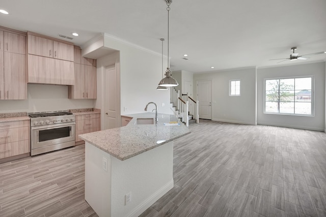 kitchen featuring visible vents, light wood-type flooring, stainless steel stove, a sink, and light brown cabinets
