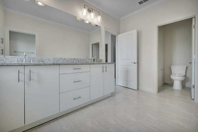 bathroom featuring crown molding, double vanity, a sink, and toilet