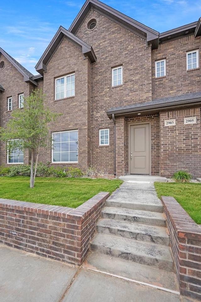 townhome / multi-family property with a front lawn and brick siding