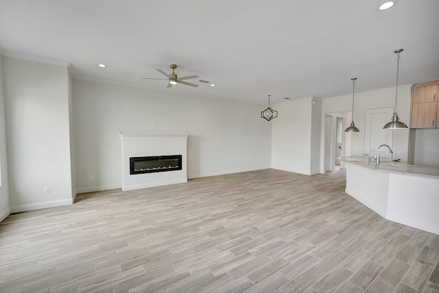 unfurnished living room with ornamental molding, a glass covered fireplace, light wood-type flooring, recessed lighting, and a ceiling fan