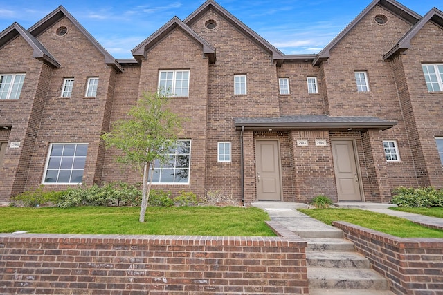 view of property featuring a front lawn and brick siding