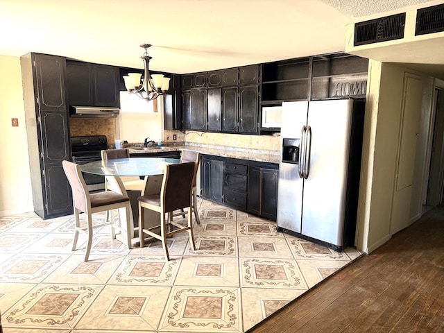 189 County Road 401-l, Seminole, TX 79360 - kitchen with appliances with stainless steel finishes, a chandelier, extractor fan, and tasteful backsplash