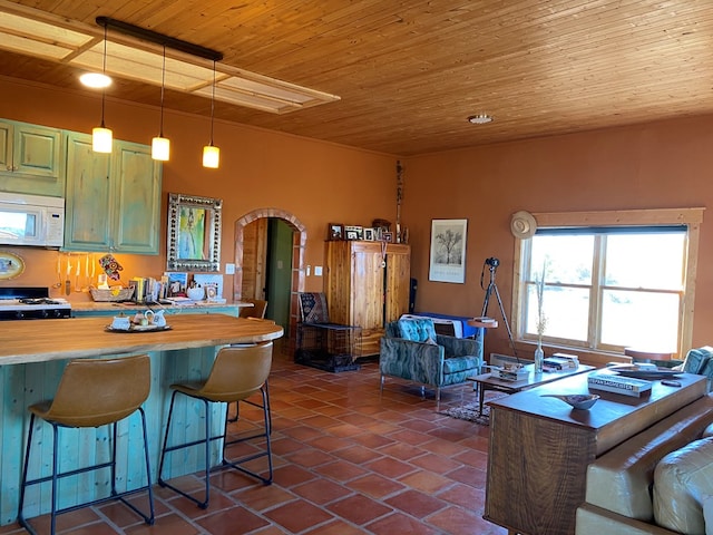 kitchen featuring wood ceiling, green cabinets, stove, hanging light fixtures, and a kitchen breakfast bar