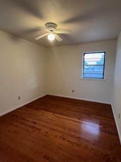 unfurnished room featuring ceiling fan and dark wood-type flooring