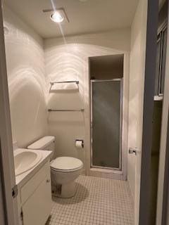 bathroom featuring tile patterned flooring, vanity, toilet, and a shower with door