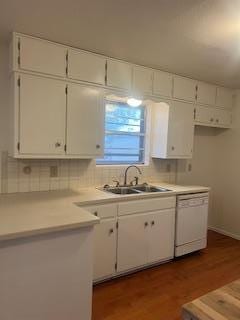 kitchen with backsplash, white dishwasher, sink, hardwood / wood-style flooring, and white cabinetry