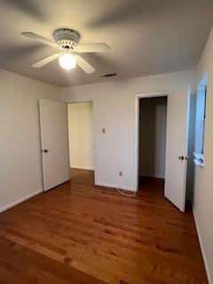 unfurnished bedroom with ceiling fan and dark wood-type flooring