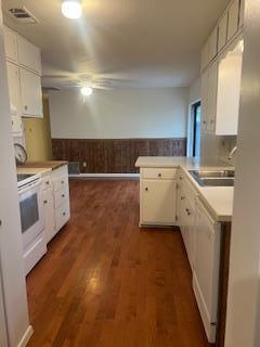 kitchen with white cabinetry, sink, dark hardwood / wood-style floors, kitchen peninsula, and white appliances