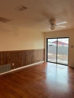 spare room featuring ceiling fan, wood walls, and wood-type flooring