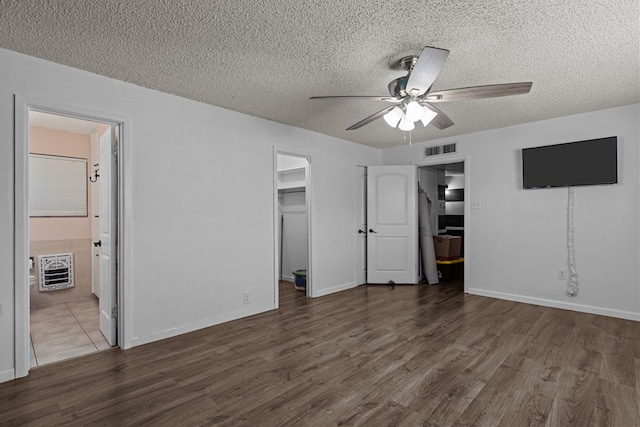 unfurnished bedroom with a walk in closet, a textured ceiling, visible vents, and wood finished floors