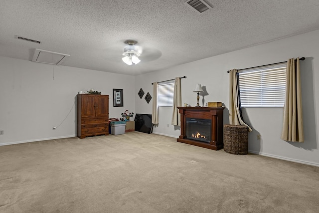interior space featuring light colored carpet, attic access, visible vents, and a glass covered fireplace