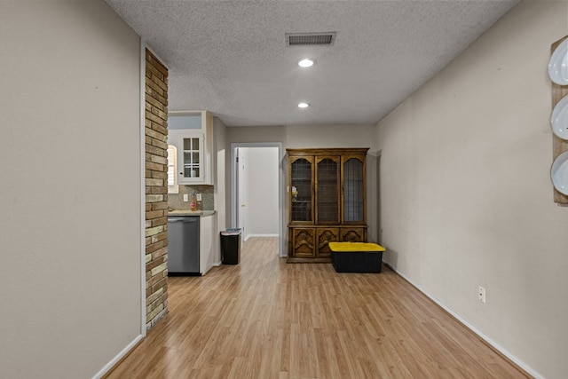 hall featuring recessed lighting, a textured ceiling, baseboards, light wood finished floors, and visible vents