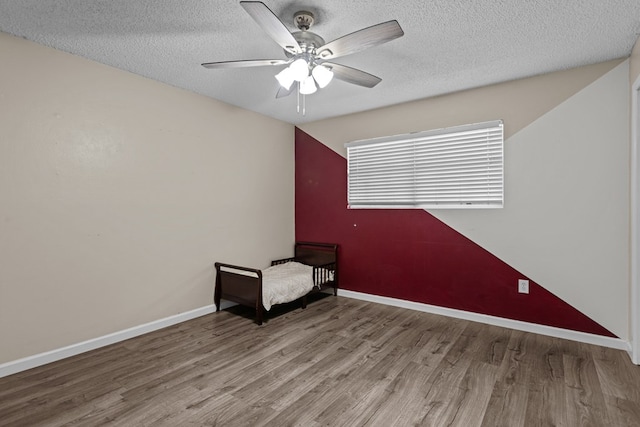 unfurnished room with a textured ceiling, baseboards, wood finished floors, and a ceiling fan
