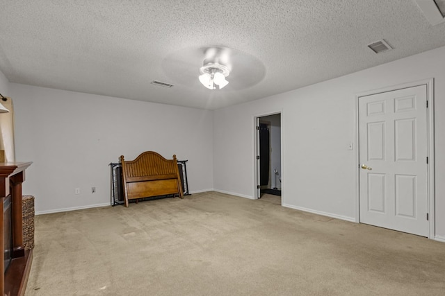 unfurnished bedroom featuring a textured ceiling, visible vents, baseboards, and light carpet