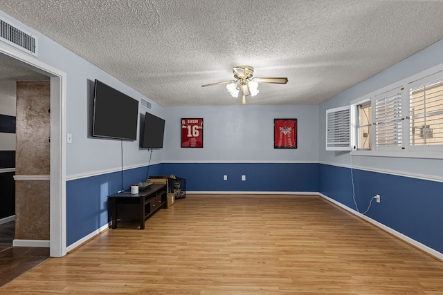 interior space featuring a textured ceiling, visible vents, wood finished floors, and a ceiling fan