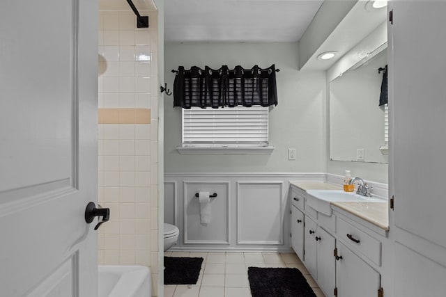 bathroom with shower / bath combination, toilet, tile patterned flooring, vanity, and a wainscoted wall