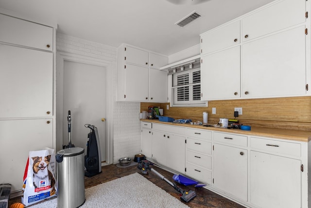 kitchen featuring light countertops, white cabinetry, visible vents, and tasteful backsplash