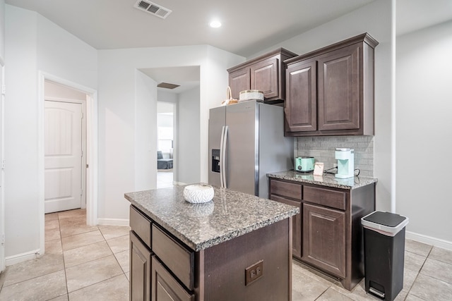 1614 Laguna Meadows Trl, Midland, TX 79705 - kitchen with stainless steel fridge, a center island, decorative backsplash, light stone countertops, and dark brown cabinets