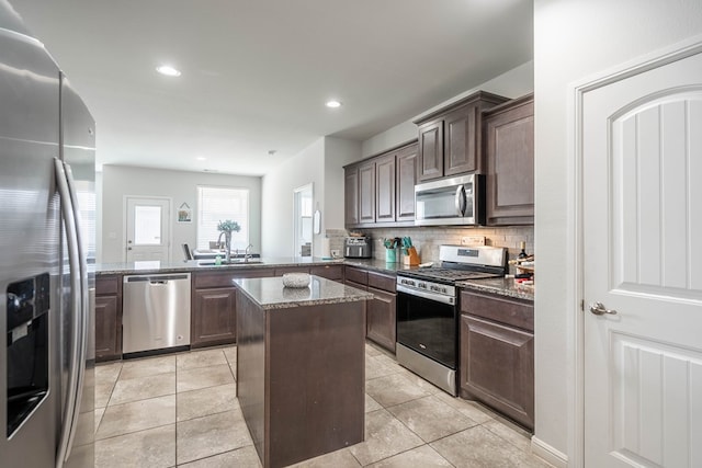 1614 Laguna Meadows Trl, Midland, TX 79705 - kitchen with appliances with stainless steel finishes, dark brown cabinets, tasteful backsplash, dark stone countertops, and a peninsula