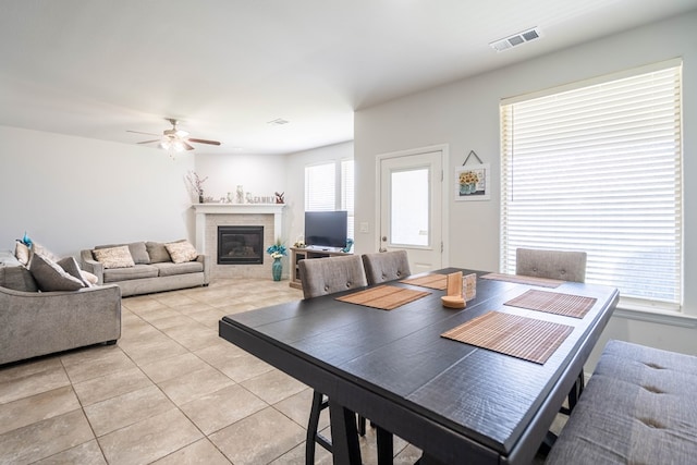 1614 Laguna Meadows Trl, Midland, TX 79705 - dining area featuring light tile patterned floors, a ceiling fan, and a glass covered fireplace