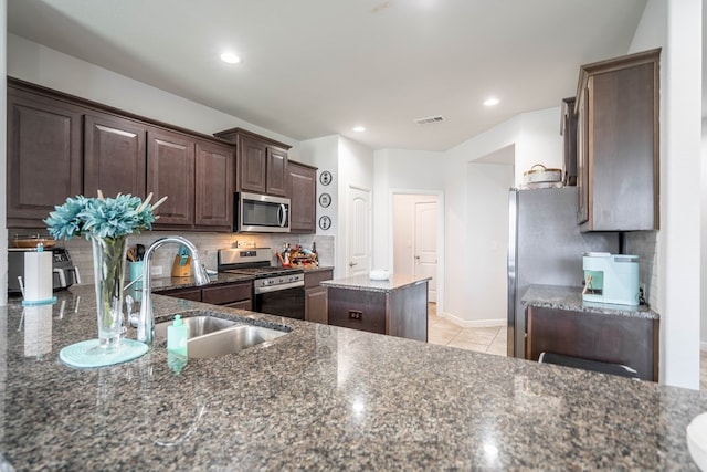 1614 Laguna Meadows Trl, Midland, TX 79705 - kitchen with stainless steel appliances, dark brown cabinets, tasteful backsplash, dark stone counters, and recessed lighting