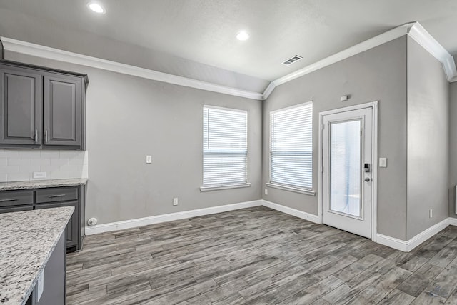 kitchen featuring gray cabinets, visible vents, baseboards, light wood-style floors, and ornamental molding