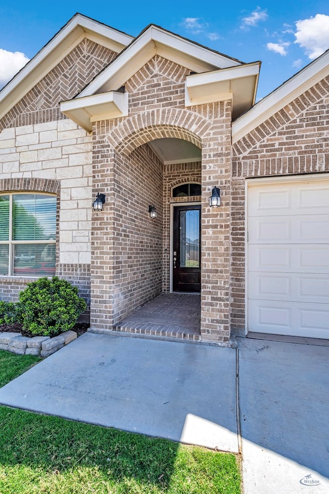 entrance to property featuring brick siding and a garage