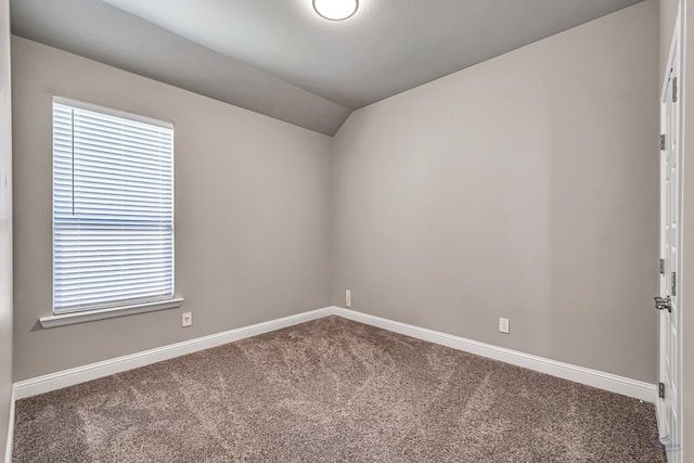 carpeted spare room featuring baseboards and vaulted ceiling