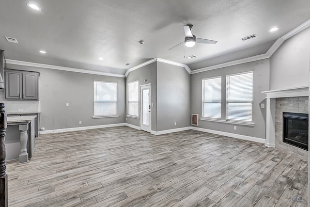 unfurnished living room featuring crown molding, light wood-style floors, visible vents, and a ceiling fan