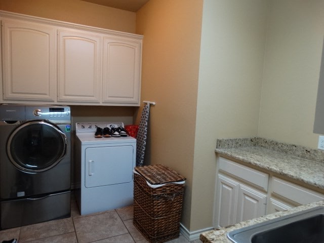 1 Warwick Dr, Odessa, TX 79765 - laundry room with cabinet space, washing machine and clothes dryer, and light tile patterned floors