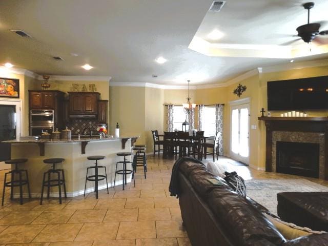 1 Warwick Dr, Odessa, TX 79765 - living area with a fireplace, ceiling fan, ornamental molding, light tile patterned floors, and a tray ceiling