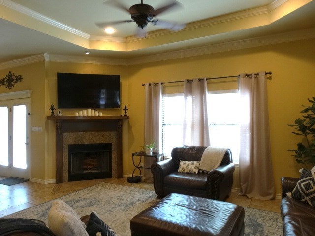 1 Warwick Dr, Odessa, TX 79765 - living area with healthy amount of natural light, a tray ceiling, tile patterned floors, ceiling fan, and crown molding