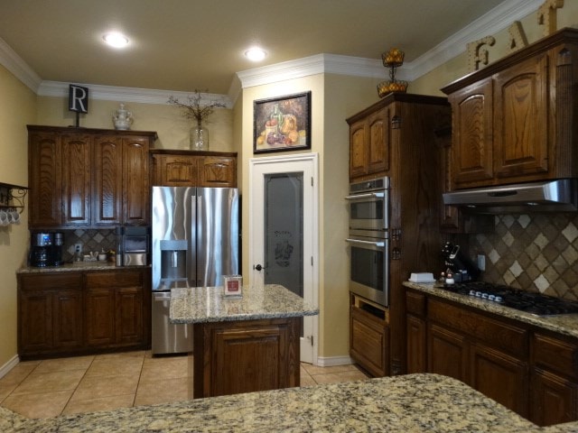 1 Warwick Dr, Odessa, TX 79765 - kitchen featuring stainless steel appliances, under cabinet range hood, light tile patterned flooring, decorative backsplash, and light stone counters