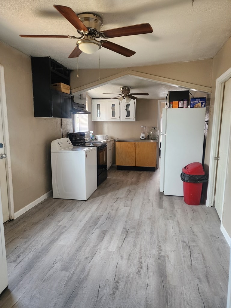407 Lindberg St, Odessa, TX 79761 - kitchen with freestanding refrigerator, washer / dryer, electric range oven, ceiling fan, and under cabinet range hood