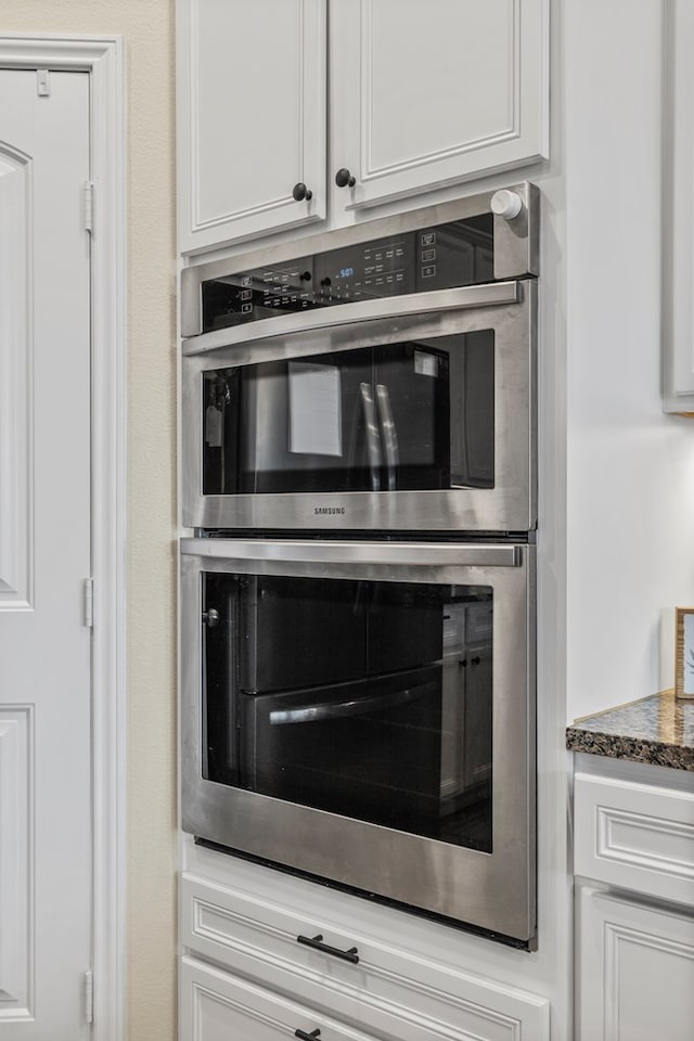 1214 Yancy St, Odessa, TX 79765 - kitchen view of stainless steel double oven, white cabinetry, and dark stone countertops