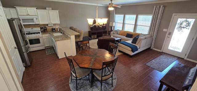 7266 Barksdale Ln, Odessa, TX 79765 - dining area featuring a chandelier, plenty of natural light, crown molding, dark wood-style flooring, and a ceiling fan